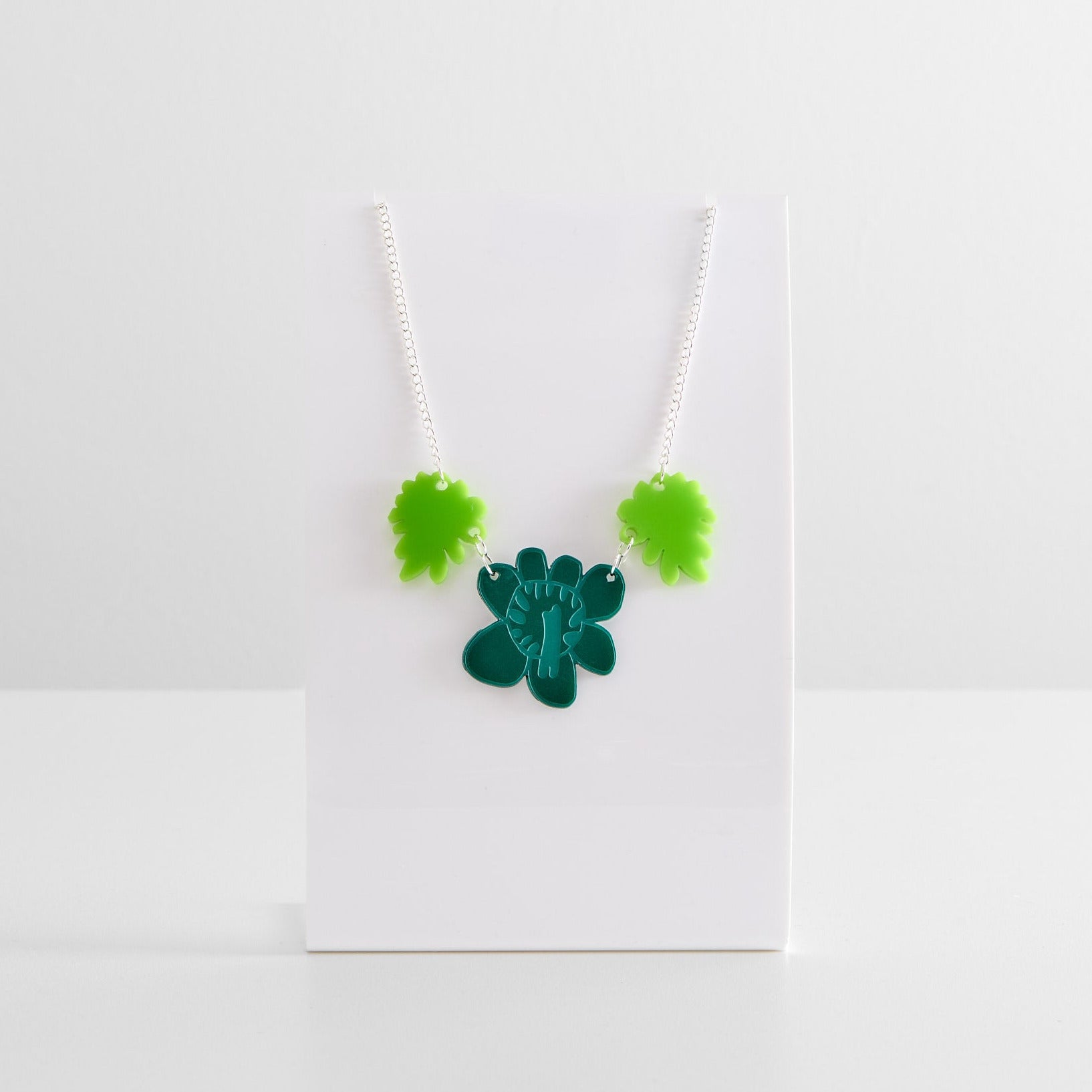 Necklace with green flower pendant on a white card